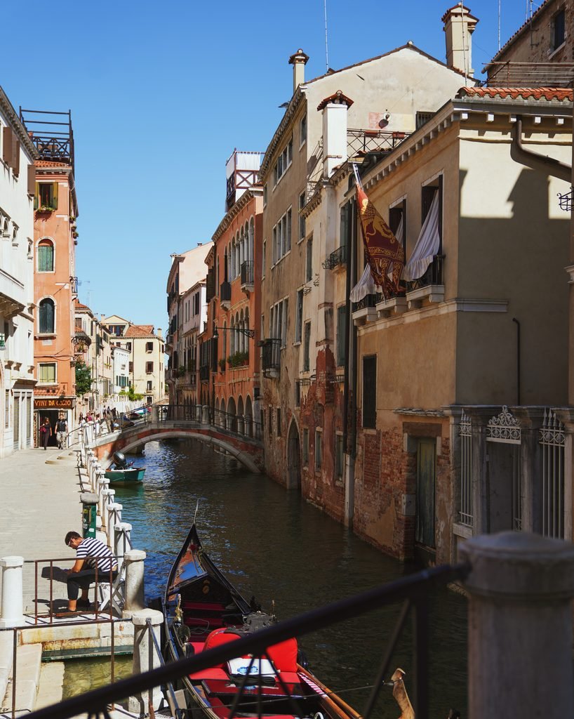 Quiet Venice canal with a moored gondola, a small bridge and colourful houses