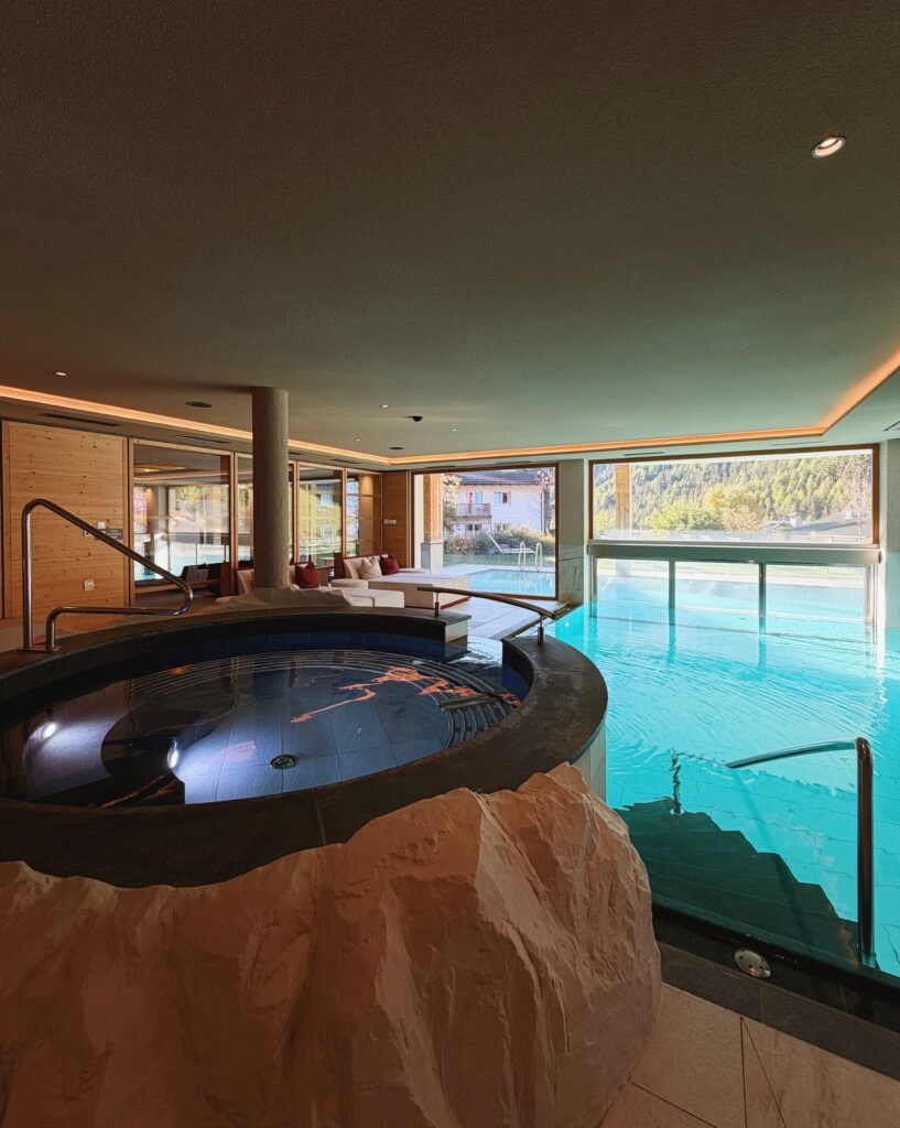 Round whirlpool beside the indoor pool in the Hotel Masl Family Spa, with big windows looking out to the garden