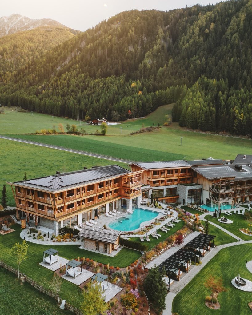 Aerial view of Hotel Masl in Valles with its outdoor pool, garden and green meadows below the forest