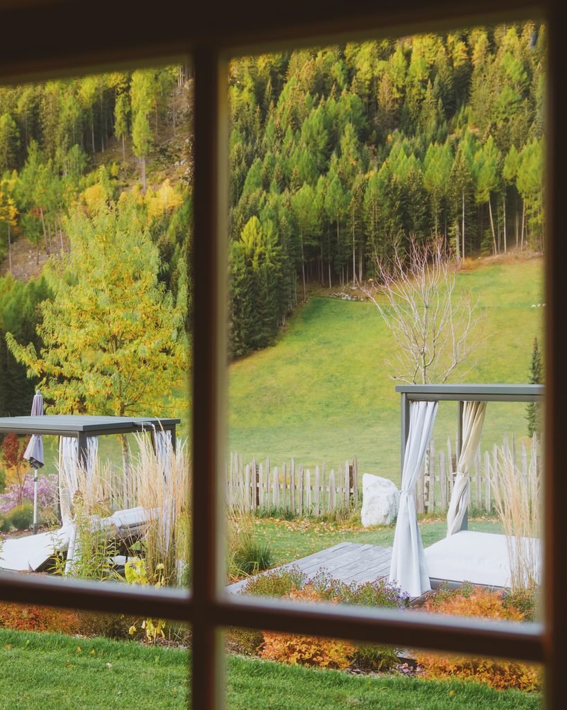 View through the spa window at Hotel Masl over the garden day beds and autumn forest