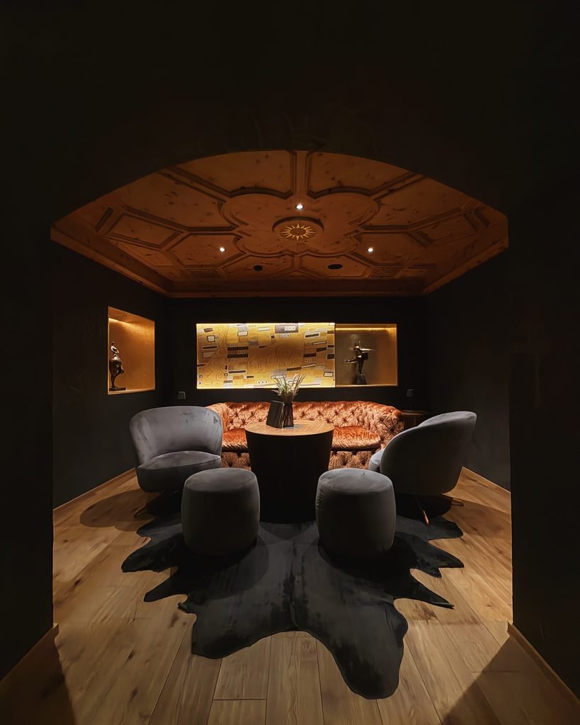 Cosy dark wood lounge with velvet armchairs and a carved ceiling at Hotel Masl