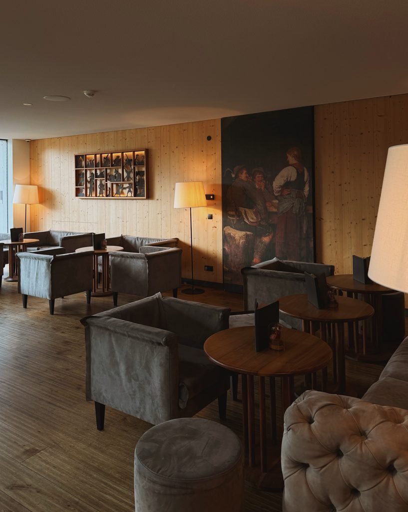 Hotel Masl bar and lounge with grey armchairs, wood panelling and a historic painting