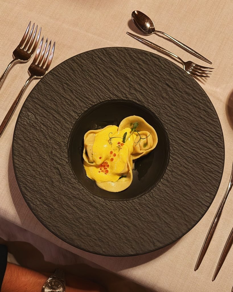 Handmade tortelloni with saffron butter served on a slate plate at the Hotel Masl five course dinner